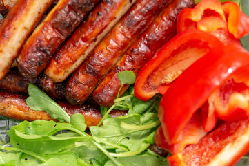 sausages are fried in the grill and arugula, red bell pepper