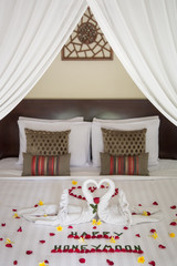 Luxury hotel bedroom interior with honeymoon decoration, Towel swans and rose flowers on the bed