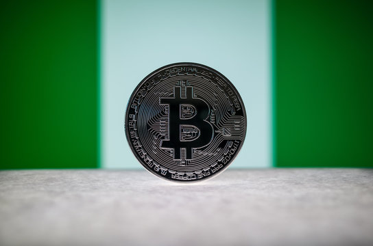 Physical silver version of Bitcoin (BTC) and Nigeria Flag on the background. Conceptual image for investors in cryptocurrency and Blockchain Technology.