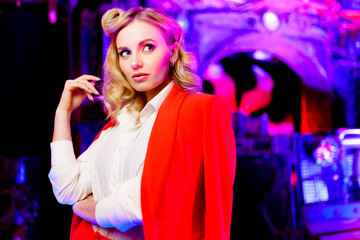 Portrait of young blonde woman in red suit in nightclub