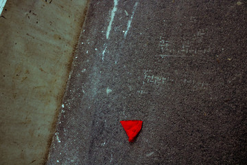 The latex fabric which remained from the burst balloon of red color which lies on the drawn white lines asphalt, with small cracks