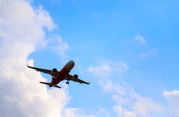 An airplane is flying in sunny day with cloudy blue sky background. 
