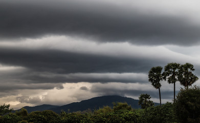 Obraz premium Scenery of black thunderstorm cloudy sky with forest and mountains.