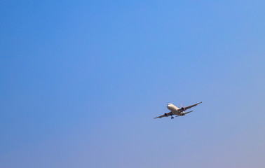 Fototapeta premium An airplane is flying in sunny day with blue sky background. 