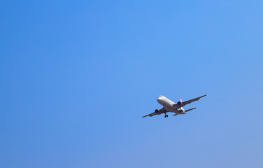 An airplane is flying in sunny day with blue sky background. 