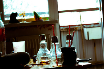 In the bottle foreground in the form of bulbs with drinks and tubules and also on each side there are thin glasses; On a background a balcony with the open street and fresh air.