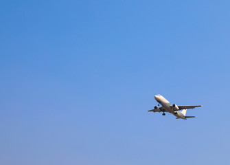 An airplane is flying in sunny day with blue sky background.