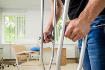 Injured man trying to walk on crutches in the hospital.