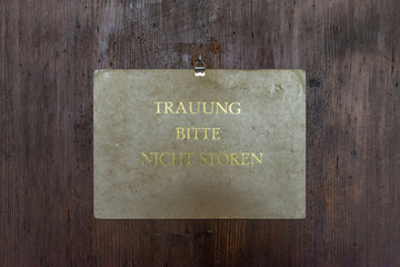 Schild zum Standesamt im alten Rathaus in Regensburg mit dem deutschen Text - Trauung bitte nicht...