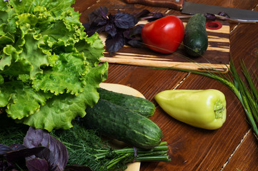 cooking green  salad from fresh organic vegetables, basilic and dill at wooden table. close up