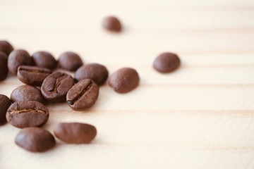 roasted coffee bean on light brown wooden texture with copy space, selective focus