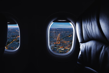 Traveling by airplane, looking through plane window and city view at night