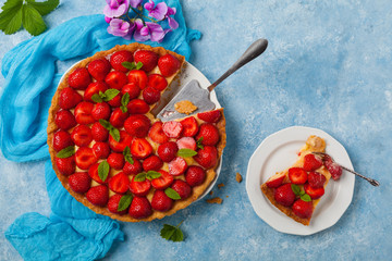 Delicious tart with strawberries on a blue painted background. Top view.