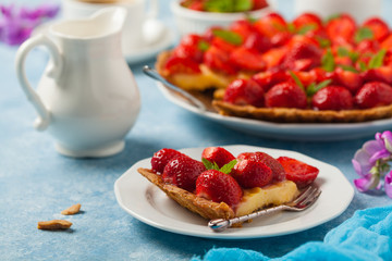Delicious tart with strawberries on a blue painted background. Front view.