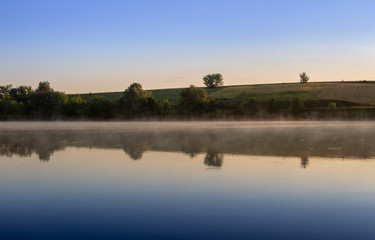 Fototapeta na wymiar Colorful sunrise on a small lake near the village
