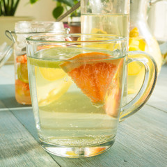 A glass with homemade lemonade from lemon and grapefruit on the table by the window