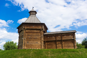 Antique wooden tower with a fragment of a wall on a hill