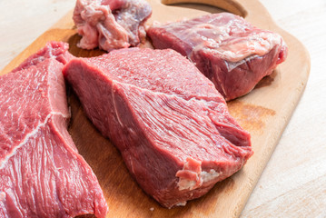 Slices of raw beef on a cutting wooden board close up