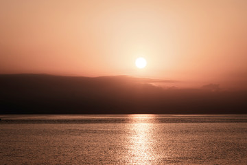 Fototapeta premium Background of morning sky with rising sun. Sun reflection in sea water. Panorama. Horizon