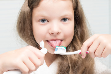 girl applying paste on a toothbrush in front of her, close-up