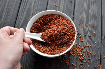 hand holdind a spoon with uncooked red rice