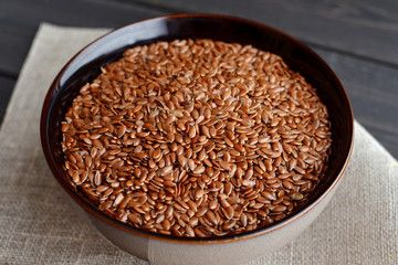 flax seeds in bowl with linen fabric on wooden background