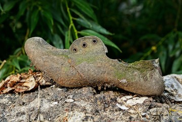 one gray dirty boot stands on the ground in nature