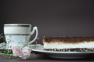 Coconut chocolate souffle cake with a cup of coffee and white сhinese cloves on a brown background