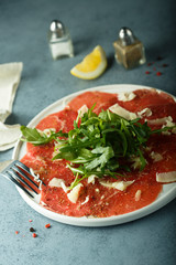Homemade beef carpaccio with cheese and arugula