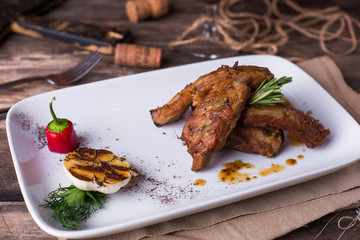 Grilled pork ribs with vegetables on a white plate