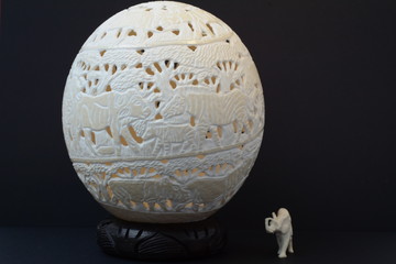Souvenirs from South Africa - an egg made from a carved real ostrich egg and a small white baby elephant on a dark background