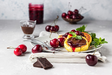 Cottage cheese pancakes or fritters with chocolate and cherry jam, fresh cherry and mint. Traditional Ukrainian and Russian cuisine. Syrniki. Healthy and diet breakfast.