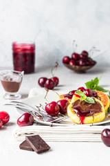 Cottage cheese pancakes or fritters with chocolate and cherry jam, fresh cherry and mint. Traditional Ukrainian and Russian cuisine. Syrniki. Healthy and diet breakfast.