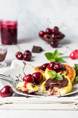 Cottage cheese pancakes or fritters with chocolate and cherry jam, fresh cherry and mint. Traditional Ukrainian and Russian cuisine. Syrniki. Healthy and diet breakfast.