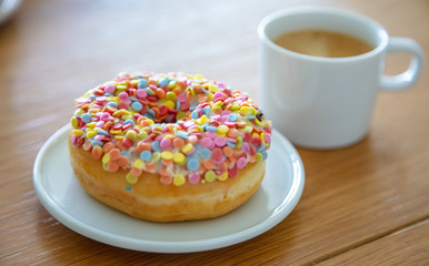 Doughnut and coffee cup on wood. Close up view
