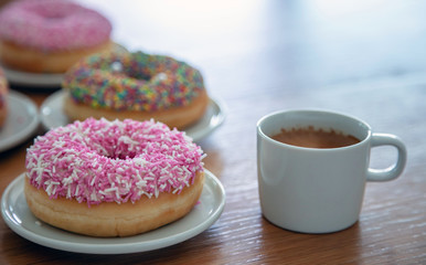 Doughnuts and coffee cup on wood. Close up view