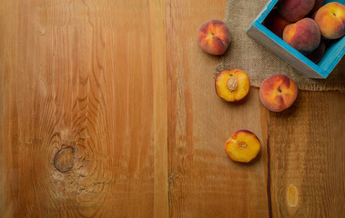 Fresh ripe peaches fruits in blue box on wooden rustic background. Top view.