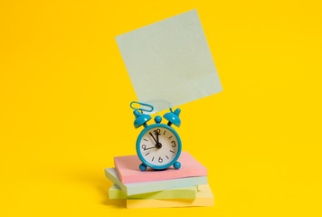 Metal alarm clock blank sticky note stacked notepads colored background