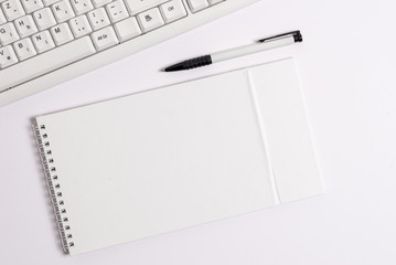White pc keyboard with empty note paper above white background.