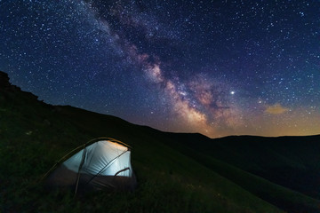 Fototapeta na wymiar Fantastic starry night with galaxy Milky Way with a tourist and a tent on the mountain range in the Ukrainian Carpathians