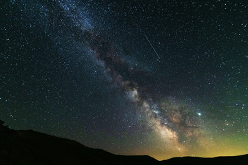 Fantastic starry night with galaxy Milky Way with a tourist and a tent on the mountain range in the Ukrainian Carpathians