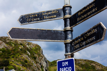Road sign on the crossroads with blue cloudy sky in the background.