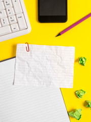 Empty crumpled white paper with copy space on the table with paper clips clock mobile and pc keyboard.