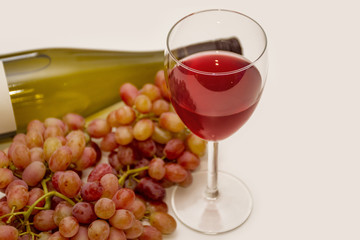 Red grapes and glass of wine on neutral background
