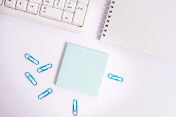 Empty note paper on the white background by the pc keyboard with copy space.