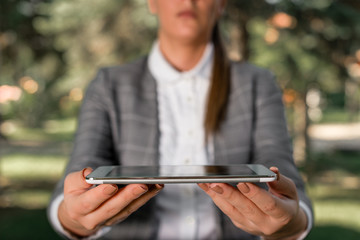 Outdoor scene with business woman holds lap top with touch screen.