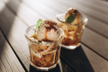 Ice ceam with chocolate and mint in glass cup on wooden table in street cafe. Food, dessert concept