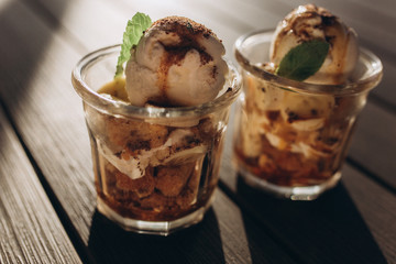 Ice ceam with chocolate and mint in glass cup on wooden table in street cafe. Food, dessert concept