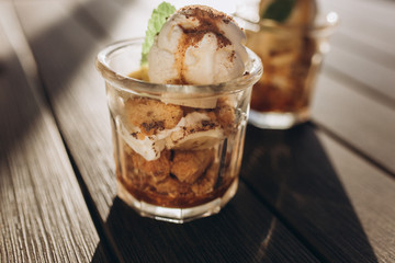 Ice ceam with chocolate and mint in glass cup on wooden table in street cafe. Food, dessert concept