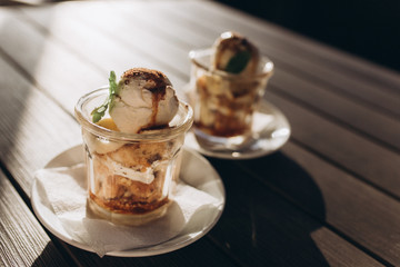 Ice ceam with chocolate and mint in glass cup on wooden table in street cafe. Food, dessert concept